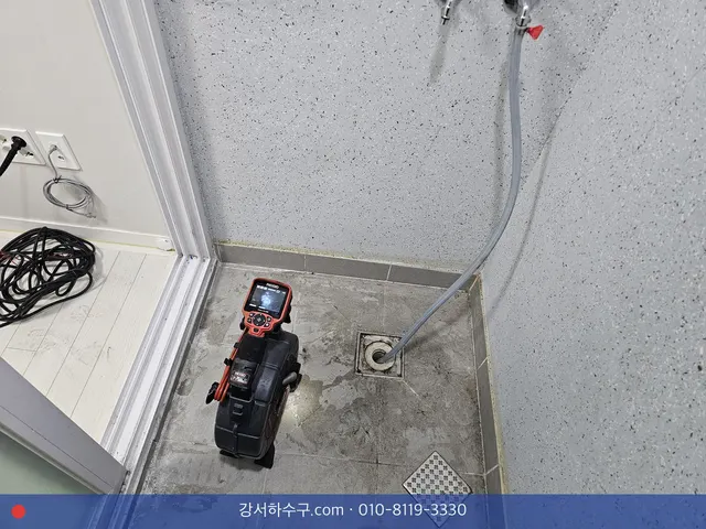 세탁 공간 바닥 배수구 옆에 세워 둔 휴대용 내시경