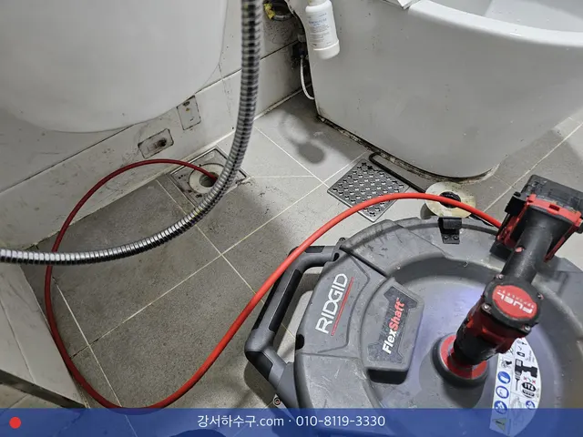 변기 옆 바닥 배수구로 스프링 케이블을 넣는 모습