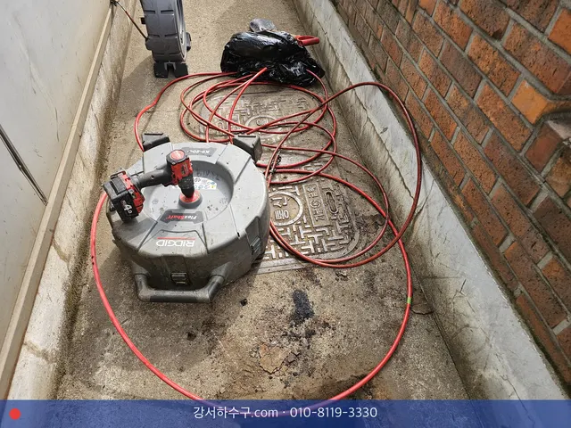 건물 옆 통로 맨홀 위의 스프링 기계와 감긴 케이블